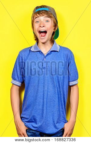 Portrait of a shouting teenage boy over yellow background. Studio shot. Teenager awkward age.