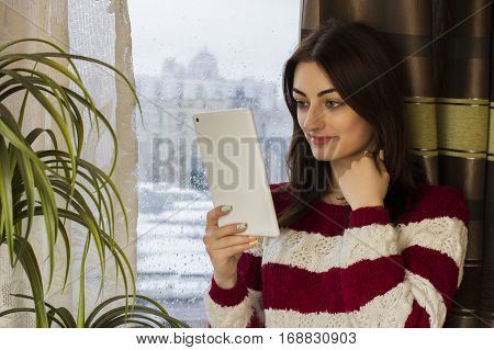 beautiful girl in a sweater keeps tablet in hand