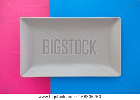 Empty gray ceramic dish on over blue and rpink wooden table rectangle dish