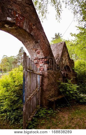 Part of an old stone arch with bench near the entrance.