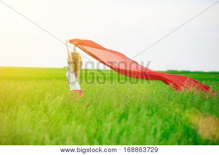 Young lady runing with tissue in green field. Beautiful happy woman walking  in the summer rural meadow. Outdoor summer portrait of pretty sport style woman jumping with fabric. Beautiful fit tan girl. Sexy slim model caucasian ethnicity outdoors.