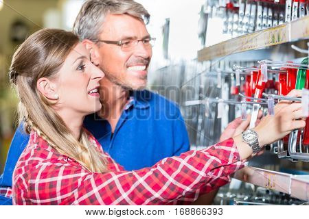 Young woman asking shop assistant in ironware department of hardware store about mountings for window boxes