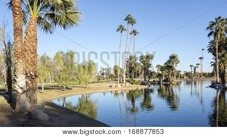 Bright and clear winter sky reflecting in deep blue water of Encanto park lake Phoenix downtown Arizona