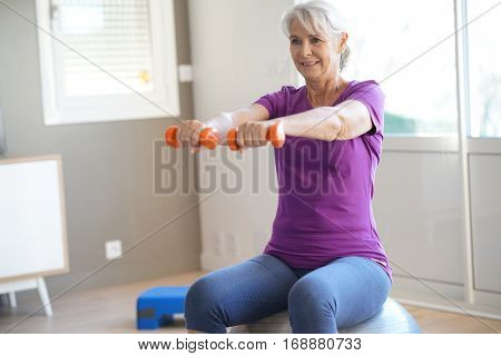 Senior woman doing fitness exercices in front of tv
