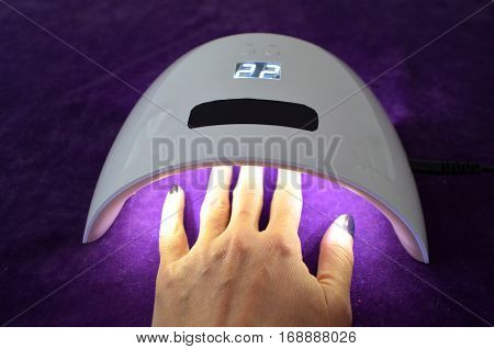 Nail gel salon. Beautiful woman hand and lamp UV  for nails UV with timer