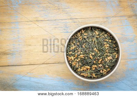 genmaicha green tea with roasted rice, a bowl against grunge wood with a copy space
