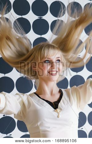 Slim blonde girl with a thick hair shakes your head and smiles for camera at the beauty salon