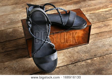 New leather sandals and gift box on wooden background
