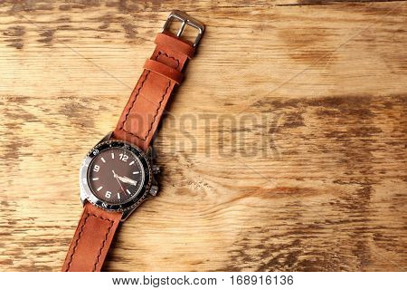 Stylish watch with leather wristlet on wooden background