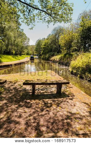 Shady tree lined view of the Llangollen canal with a narrowboat tied up on the bank a beautiful part of the British inland waterway network