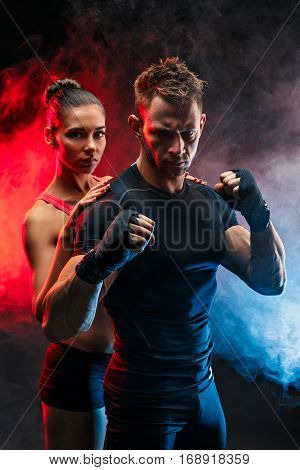 Strong boxer in stance with handwraps on his fists. With girlfriend standing behind him.