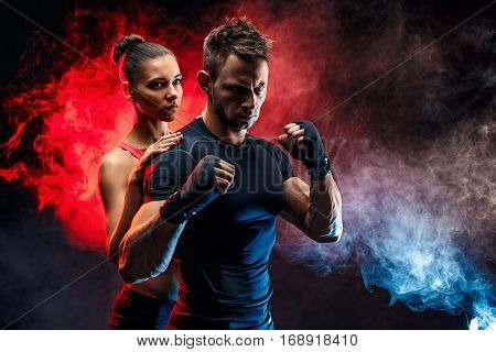 Strong boxer in stance with handwraps on his fists. With girlfriend standing behind him.