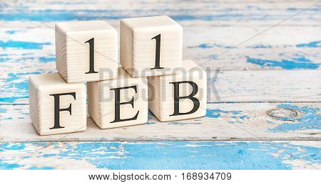 February 11th. Wooden cubes with date of 11 February on old blue wooden background.