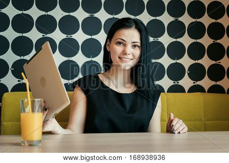 Brunette model aged 20s sitting at the table poses for camera indoors