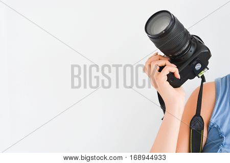 Woman holding a professional DSLR camera above her shoulder suggesting her being a professional photographer