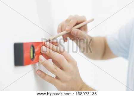 Mid-adult man marking on wall with level