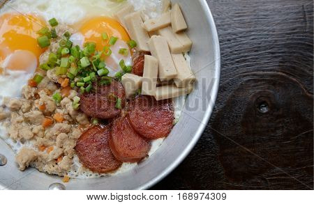 Top view closeup sausage pork pan fried eggs breakfast menu in a pan with wooden background healthy concept.