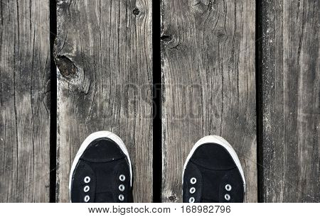 Black and white Shoes stand on old wooden pier floor. Wood pier abstract texture of a natural gray. View of old weathered deck wooden board.