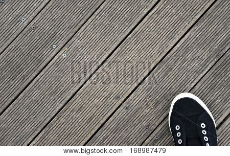 Black and white Shoes stand on old wooden pier floor. Wood pier abstract texture of a natural gray. View of old weathered deck wooden board. Diagonal wood background texture.