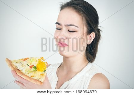 unhappy woman with piece of pizza on white background
