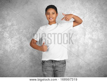 Young African American boy in blank white t-shirt standing against textured wall