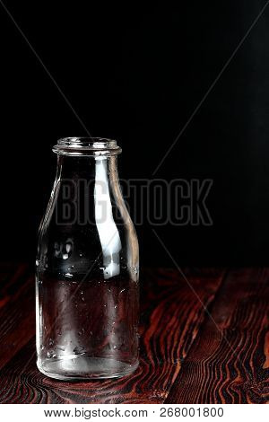 Bottle Of Milk On A Black Background And Wooden Table