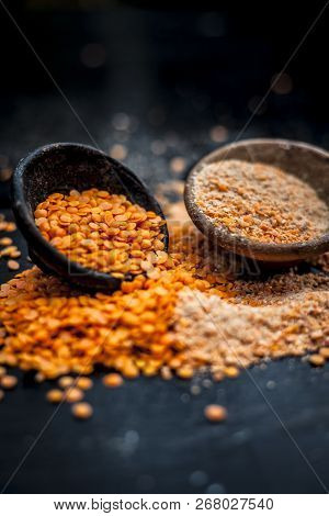 Close Up Of Raw Pink Lentils In A Clay Bowl On Wooden Surface With Its Powder.