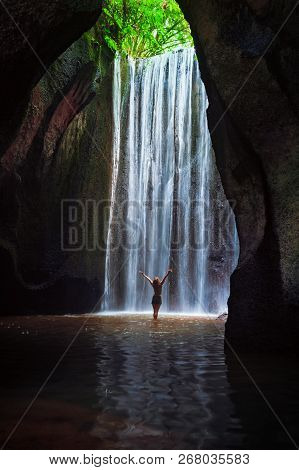 Woman Stand In Underground Cave Pool Under Falling Fresh Water Of Tukad Cepung Waterfall. Nature Day