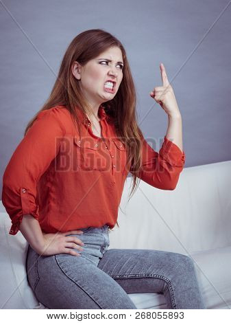 Angry, Pissed Off Young Woman. Attractive Female With Long Brown Hair Sitting On Sofa Being Mad And 