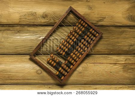 Old Hand Abacus Hanging On A Nail On The Wall Of Wooden Logs.