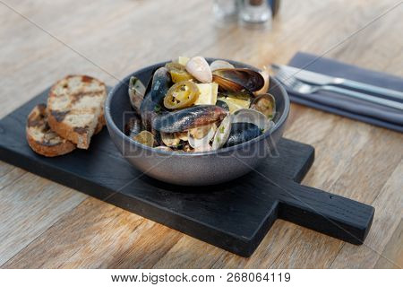 Shelfish sautee with fried bread loafs on restaurant table
