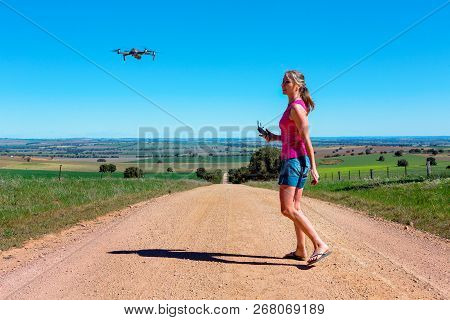 Woman Flying A Drone In A Rural Landscape With Agricultural Fields Countryside