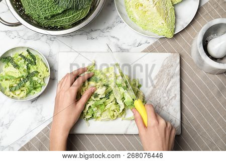 Woman Cutting Savoy Cabbage On Marble Board At Table, Top View
