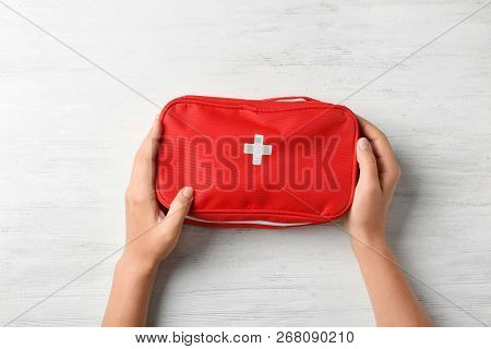 Woman Holding First Aid Kit On Wooden Background, Top View