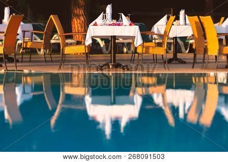 Chairs And Table Near Pool At Hotel Restaurant. Cutlery And Napkings On Tables. Resort Life On Holid