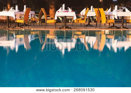 Chairs And Table Near Pool At Hotel Restaurant. Cutlery And Napkings On Tables. Resort Life On Holid