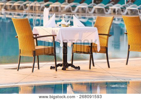 Chairs And Table Near Pool At Hotel Restaurant. Cutlery And Napkings On Tables. Resort Life On Holid