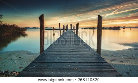 Beautiful Morning At The Lake On A Long Jetty With Wooden Planks, Morning Dew And A Colorful Sunrise