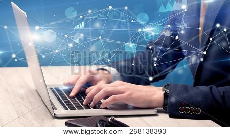 Businessman typing on laptop with linked reports charts grapghs around