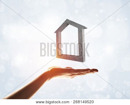 Close Up Of Hand Presenting Stone House Symbol In Palm. Mixed Media
