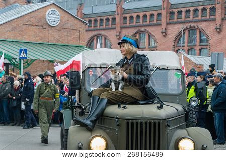 Gdansk, Poland - November 11, 2018: Woman In Historical Soldier Uniform With Dog On The Car. On The 