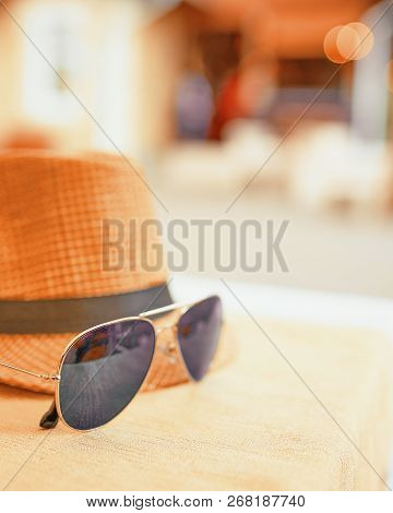 Hat And Dark Sunglasses On A Hot Day Off On The Table. Resort Concept
