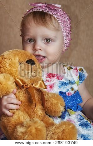Happy One Year Old Girl Playing And Posing With A Yello Teddy Bear