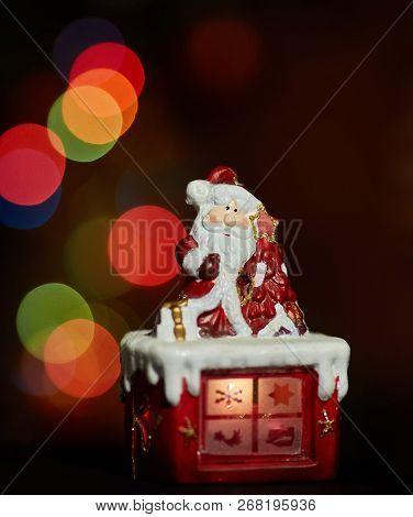 Santa Claus Statuette Doing An Exercise Waiting For Christmas. Colored Bokeh