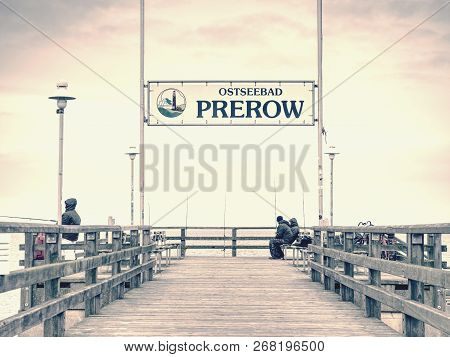 Prerow, Germany January 25 2018: Fishers On Sea Bridge Fishing In Baltic Sea.  Cold Overcast Day.