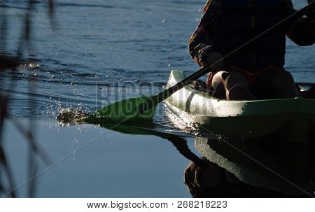 Green Kayak And Paddle Skimming Pond Water