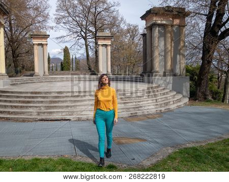 Enjoying Girl Walking In The Park With The Head Turned Towards The Spring Sun. Alps In Sight, Amphit
