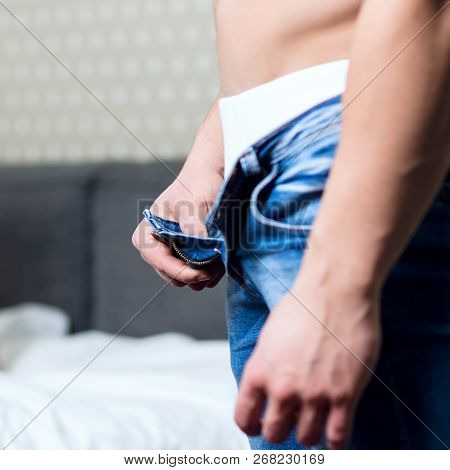 Young Man With Athletic Body Unzips His Jeans In The Bedrom.