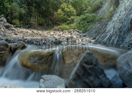 Mountain River With Rapid Stream And With Bright Blurred Waves. Big Mossy Boulders In Clear Water.