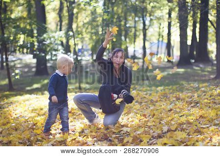 A Photographer Takes Pictures Of A Child At An Autumn Photo Shoot